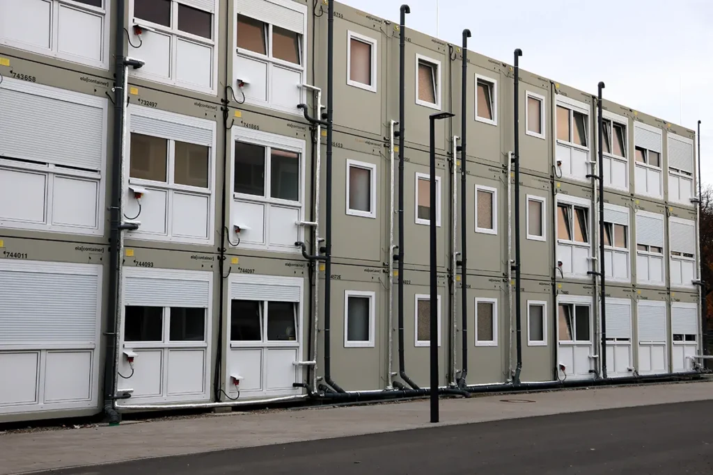Gestapelte Wohncontainer mit Regenrinnen an der Rückwand.